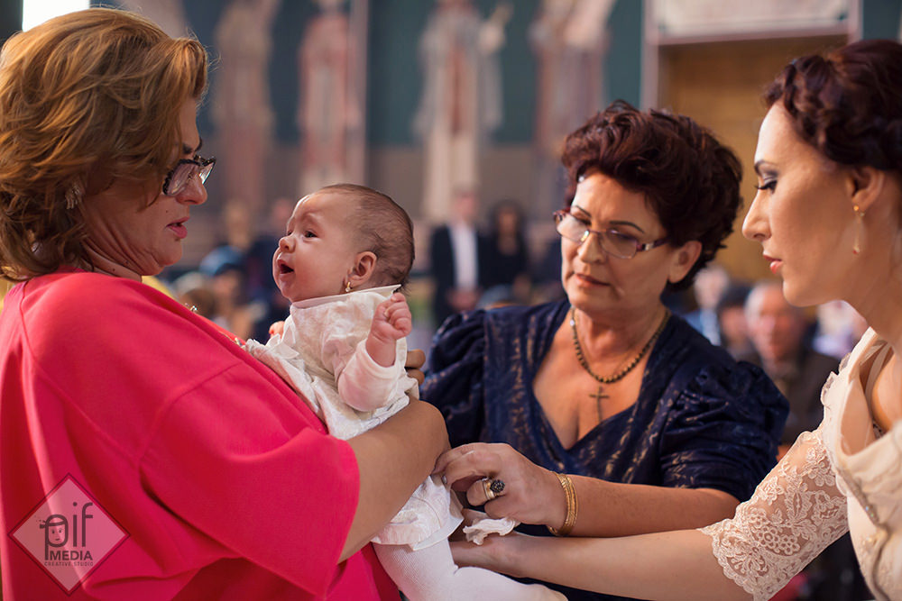 mama, bunica si nasa incearca sa imbrace copilul dupa scalda de botez