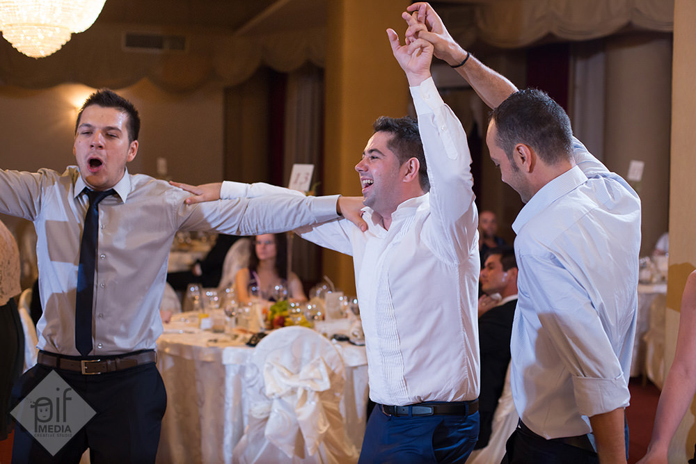 trei baieti danseaza cu multa energie la nunta