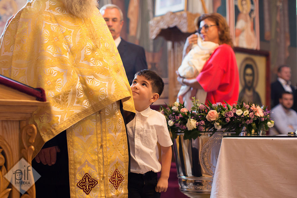 un copil de la botez se uita cu admiratie catre preot