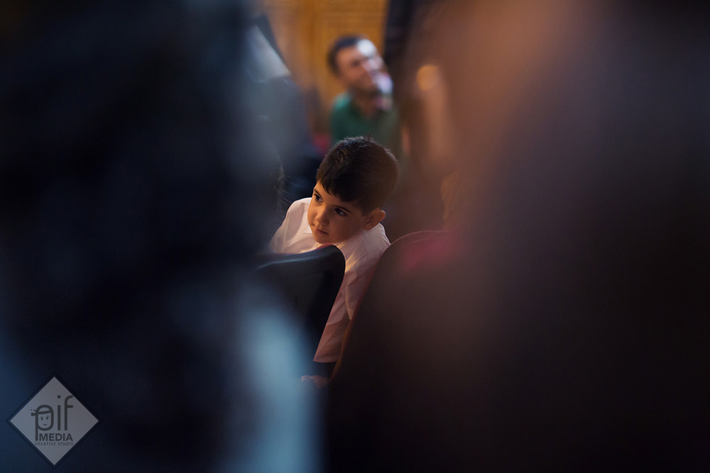 un copil se uita printre invitati la icoanele din biserica